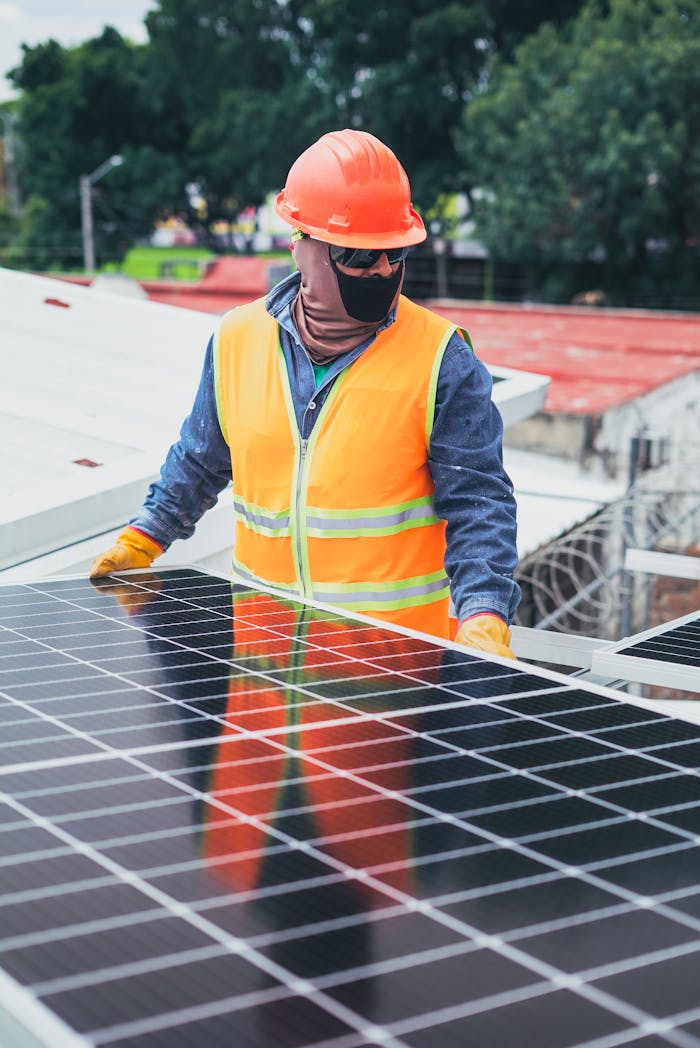 Servicios Technician in protective gear installing solar panels on a sunny day.