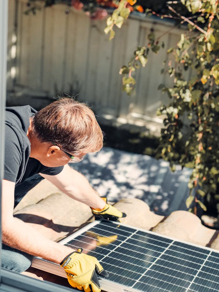 Servicios An adult male installing a solar panel on a rooftop, highlighting clean energy technology.